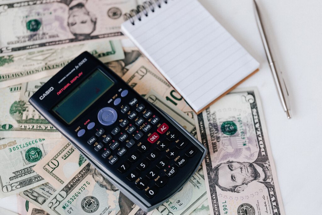 A calculator placed on a pile of dollar bills