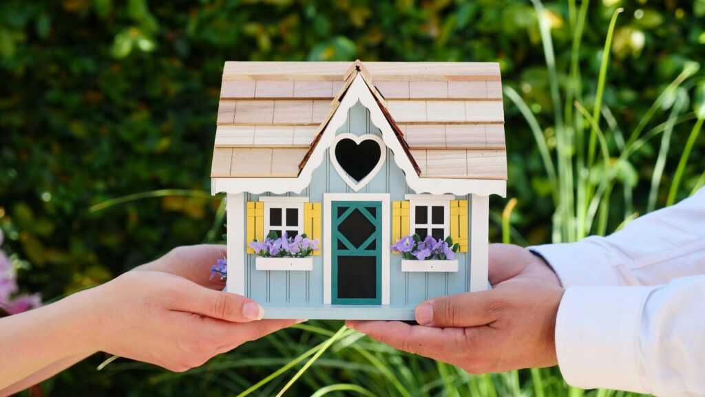 Two people holding a miniature house from a mortgage loan